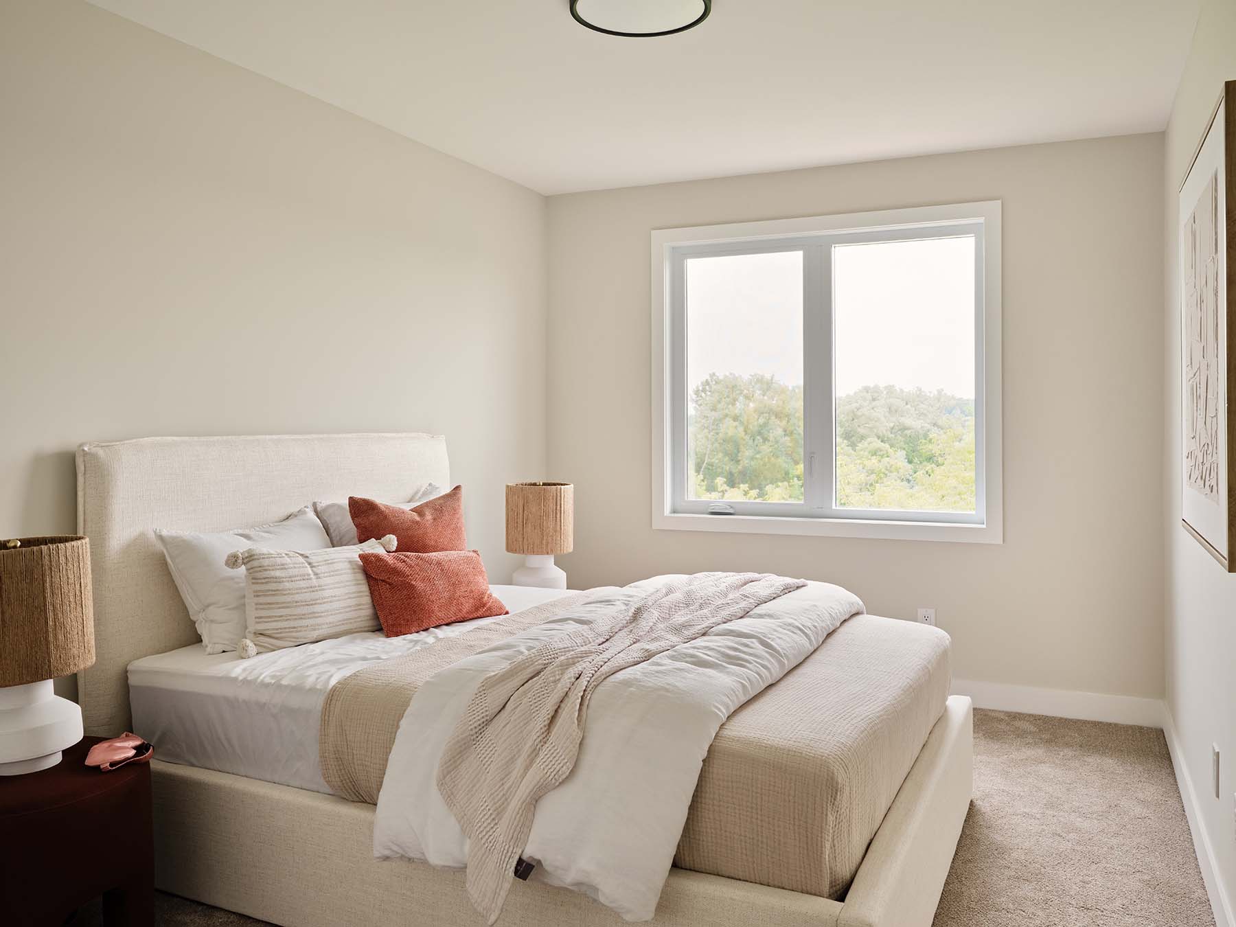 Bright bedroom with neutral decor and treetop view